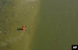 An Indian man washes his clothes in the Ganges River.