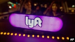 FILE - Lyft’s new Amp glows on the dashboard of a car in San Francisco, Feb. 9, 2017.