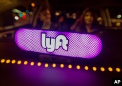 FILE - Lyft’s new Amp glows on the dashboard of a car in San Francisco, Feb. 9, 2017.