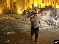 Opposition demonstrators run away as police fired a volley of tear gas against them at Georgian Parliament during a protest in Tbilisi, Georgia, June 21, 2019.