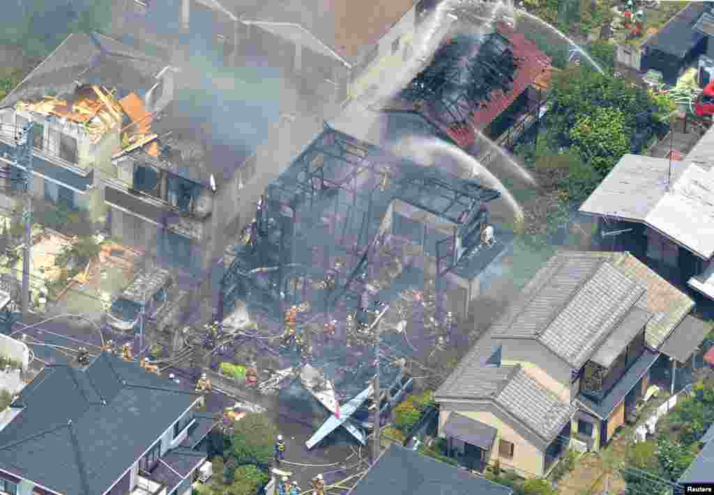 An aerial view shows debris of a crashed light plane (bottom C) and burning houses are seen after the plane went down in a residential area and burst into flames, in Chofu, outskirt of Tokyo, in this photo taken by Kyodo.