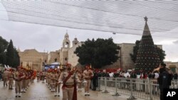 Anggota band pramuka Palestina berparade melalui Manger Square di Gereja Kelahiran, yang secara tradisional diyakini sebagai tempat kelahiran Yesus Kristus, selama perayaan Natal, di kota Betlehem, Tepi Barat, Jumat, 24 Desember 2021. (Foto: AP)