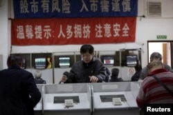 FILE - Investors look at computer screens showing stock information on the first trading day after the week-long Lunar New Year holiday at a brokerage house in Shanghai, China, Feb. 15, 2016.