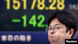 A pedestrian walks past an electronic board showing the Japan's Nikkei average outside a brokerage in Tokyo, August 6, 2014.