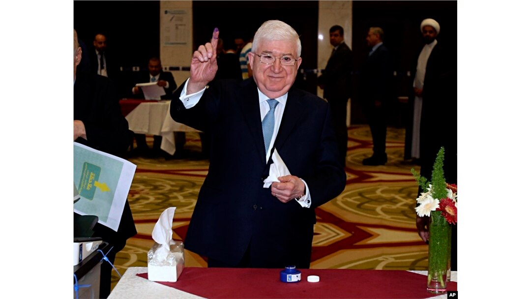 FILE - Then-Iraqi President Fuad Masum shows his ink-stained finger after casting his vote in the country's parliamentary elections in the heavily fortified Green Zone in Baghdad, Iraq, May 12, 2018.