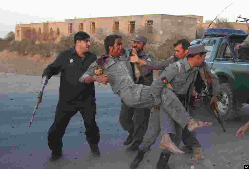 Afghan security personnel assist an injured police after a suicide car bombing and a gunfight near the U.S. consulate in Herat, Afghanistan, Sept. 13, 2013. 