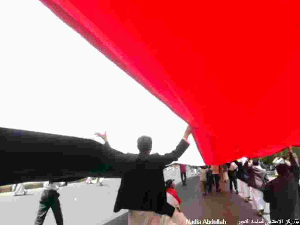 Protesters walk under a giant Yemen flag. (Photo - Nadia Abdullah)