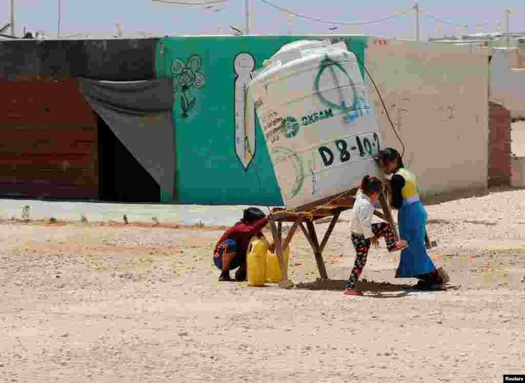 요르단 시리아 접경 마을 마프라크의 알자타리 난민촌에서 시리아 출신 어린이들이 물통에 물을 받고 있다.