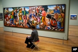 Hale Woodruff's 1942 painting "Opening Day at Talladega College," is displayed as a docent takes notes at the High Museum of Art in Atlanta, Feb. 6, 2017.