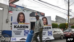 A man walks past political propaganda in the streets of the Iztapalapa neighborhood in Mexico City on June 26, 2018. Elections will take place in Mexico on July 1. Since campaigns kicked off in September, 113 politicians have been killed across Mexico.