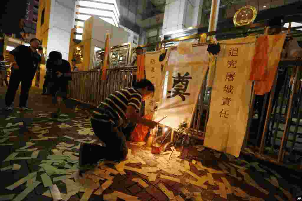 A protester prays for those killed during the China's crackdown on pro-democracy protests on Tiananmen Square during a memorial outside the Chinese liaison office in Hong Kong, June 3, 2014.