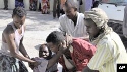 Residents assist a victim who was injured during shelling in Mogadishu's restive Bakara market (File Photo)