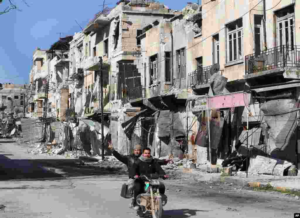 Men ride a scooter past buildings damaged by shelling from Syrian forces, Maarat al-Nuaman, Idlib province, Syria, Feb. 26, 2013.