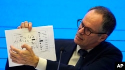 In this Feb. 9, 2021, file photo, Peter Ben Embarek of the World Health Organization team holds up a chart showing pathways of transmission of the virus during a joint news conference at the end of the WHO mission in Wuhan in central China's Hubei provinc