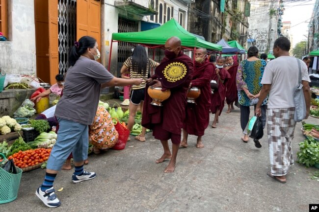 Buddhist monks collect alms from people during their morning walk at the Bogalay Zay Market in Botahtaung township in Yangon, Myanmar, Nov. 12, 2021.