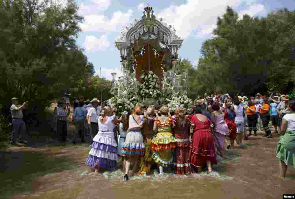 Pilgrims push a carriage as they cross the Quema River on their way to the shrine of El Rocio in Aznalcazar, southern Spain.