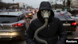 A climate activist wears a gas mask while walking in between traffic lanes during a protest against worrying levels of air pollution in Romanian cities, in Bucharest, Romania, February 14, 2020. (Inquam Photos/Octav Ganea via REUTERS)