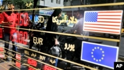 FILE - Various currency rates are displayed at a window of an exchange shop in downtown Tehran, Iran, Sept. 5, 2018. 