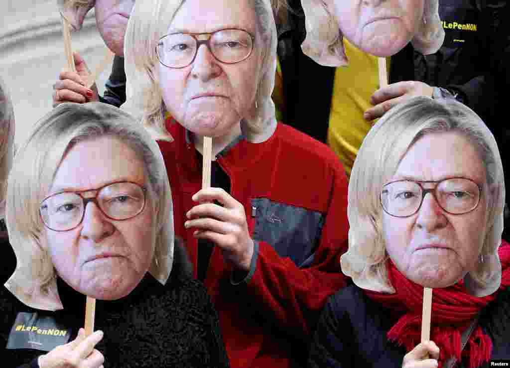 Activists wear masks depicting the face of Jean-Marie Le Pen, the founder of the French far-right National Front, with the hair of his daughter Marine Le Pen, French National Front (FN) candidate for 2017 presidential election, during a demonstration as part of traditional May Day march in Paris, May 1, 2017.