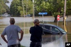 FILE - Residents survey the flood water on Old Jefferson Highway at Bayou Manchac in Prairieville, La., Tuesday, Aug. 16, 2016.