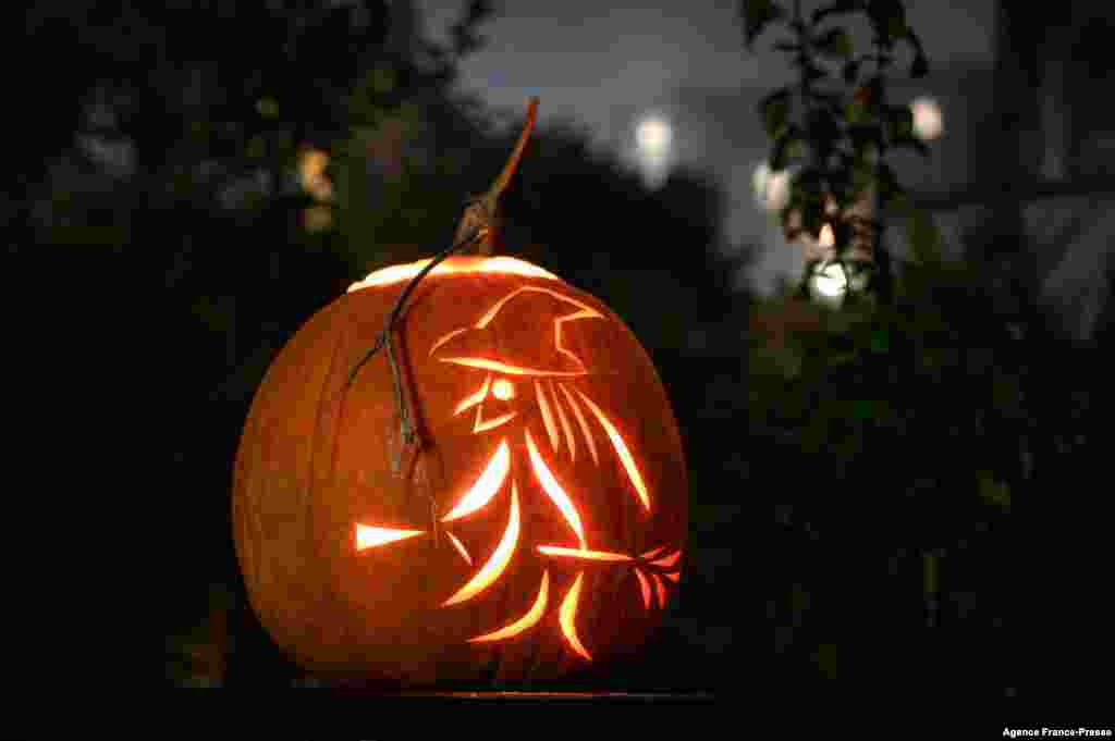 A jack-o&#39;-lantern made with a carved pumpkin representing a witch and her broom, during Halloween night, in Lausanne, Switzerland, Oct. 31, 2021.