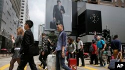 FILE - Mainland Chinese tourists carry suitcases as they walk at a shopping district in Hong Kong, April 12, 2015.