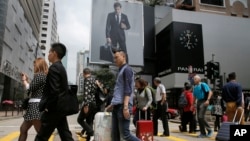 FILE - Mainland Chinese tourists carry suitcases as they walk at a shopping district in Hong Kong, April 12, 2015.