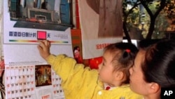 A girl in her mother's arms touches a 1997 calender printed with pictures of Hong Kong sceneries Tuesday, Dec. 24, 1996 in Nanning, capital of Guangxi Zhuang Autonomous Region. Calenders concerning with Hong Kong sceneries became best seller at the year e