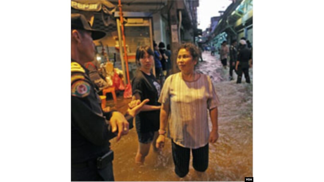 Warga berbincang-bincang dengan seorang polisi di tengah-tengah naiknya level air rendaman di daerah pusat kota Bangkok, Rabu (26/10).
