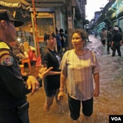 Warga berbincang-bincang dengan seorang polisi di tengah-tengah naiknya level air rendaman di daerah pusat kota Bangkok, Rabu (26/10).