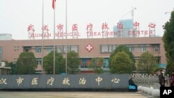 People stand outside the Wuhan Medical Treatment Center, where some infected with a novel coronavirus are being treated, in Wuhan, China, Tuesday, Jan. 21, 2020.