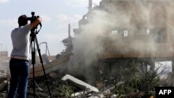 A journalist films the wreckage of a building described as part of the Scientific Studies and Research Centre (SSRC) compound in the Barzeh district, north of Damascus, during a press tour organized by the Syrian Information Ministry, on April 14, 2018.