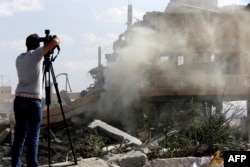 A journalist films the wreckage of a building described as part of the Scientific Studies and Research Center (SSRC) compound in the Barzeh district, north of Damascus, during a press tour organized by the Syrian information ministry, on April 14, 2018.