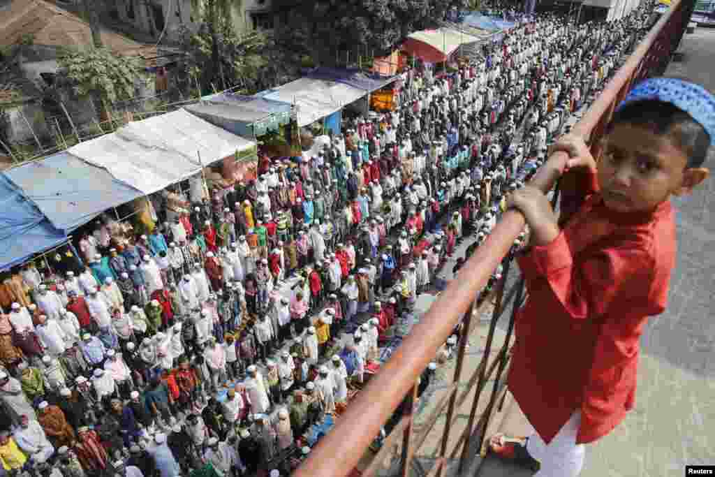 A boy watches on as devotees take part in Friday prayers during the Biswa Ijtema in Dhaka, Bangladesh. Thousands of Muslims joined the first phase of the Bishwa Ijtema (World Congregation), the second biggest gathering of Muslims after the Haj.