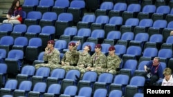 Soldiers sit in the empty seats held by the IOC as they watch the women's gymnastics qualification in the North Greenwich Arena during the London 2012 Olympic Games July 29, 2012.