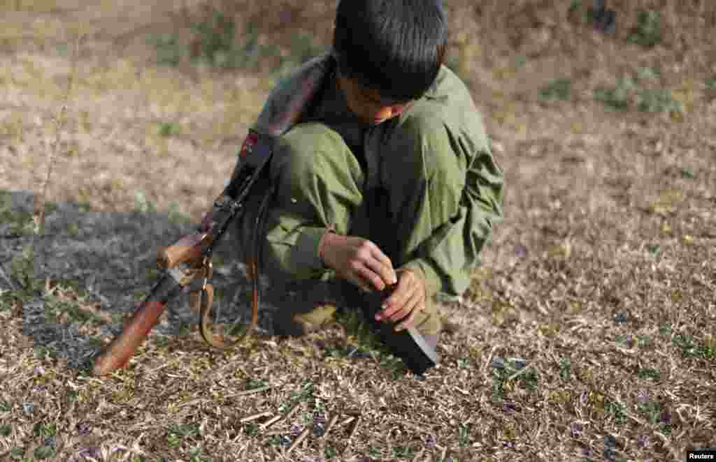 A 15-year-old rebel soldier of the Myanmar National Democratic Alliance Army (MNDAA) inserts bullets into the clip of his rifle near a military base in Kokang region March 11, 2015. Fighting broke out last month between Myanmar&#39;s army and MNDAA, which groups remnants of the Communist Party of Burma, a powerful Chinese-backed guerrilla force that battled Myanmar&#39;s government before splintering in 1989.