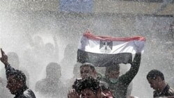 معترضین با تکان دادن پرچم مصر در مقابل ماشین های آبپاش پلیس ایستاده اند