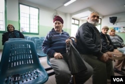 In a waiting room in a UNRWA clinic in southern Beirut, Palestinians Ahmad Said, second from left, and Abed Ghosein, third from left, await treatment. (J. Owens/VOA)
