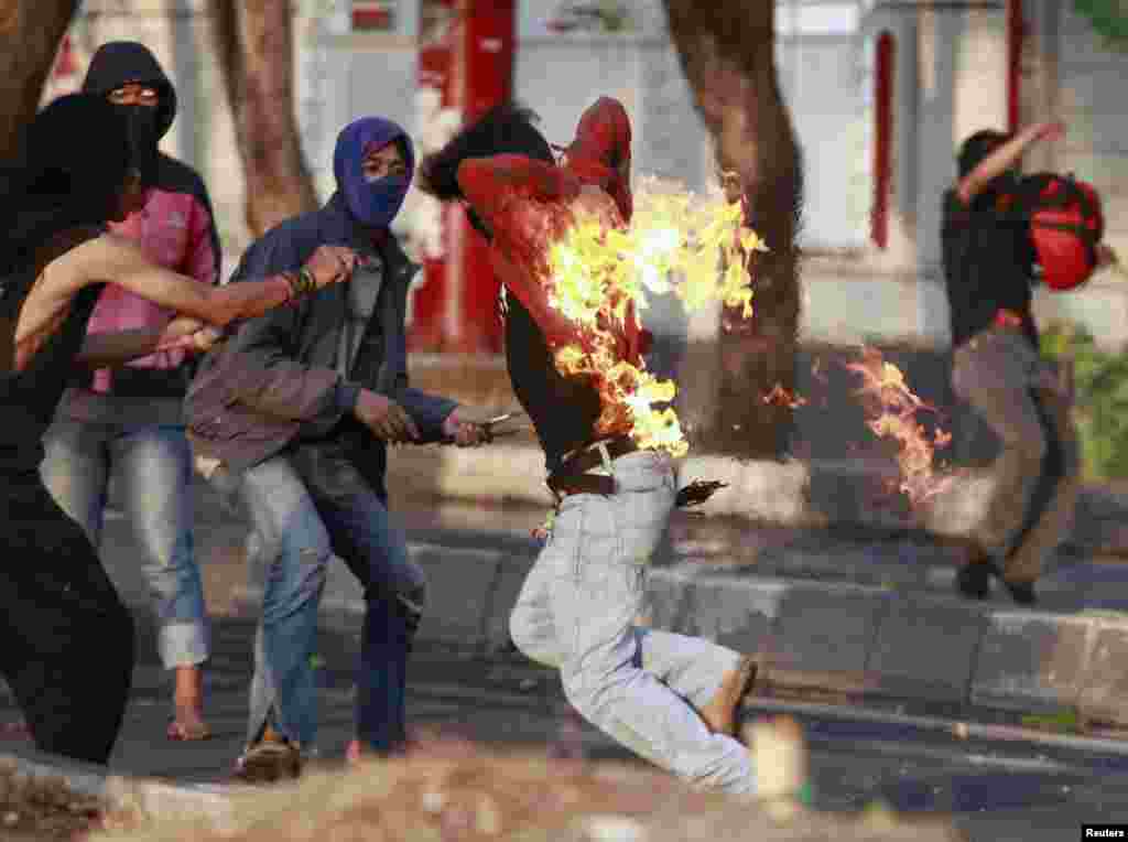 An Indonesian student protester runs after he caught fire while throwing a molotov cocktail towards police during a protest against the new president&#39;s decision to increase fuel prices this week in Makassar, South Sulawesi Province, Indonesia.