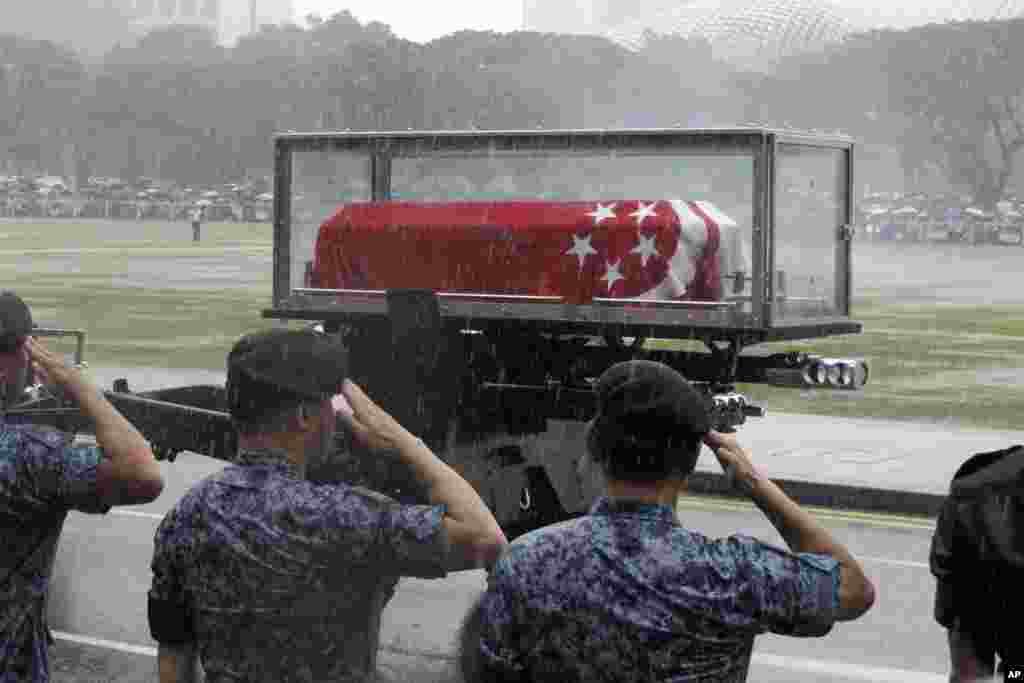 Standing in a downpour, Singaporean soldiers salute as the coffin of Lee Kuan Yew passes during the funeral procession at the Padang parade grounds and City Hall in Singapore, March 29, 2015.