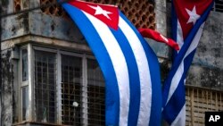 FILE - Cuban flags drape the windows of the home of Yunior Garcia Aguilera, which block his windows and prevent his communicating with the outside, in Havana, Cuba, Nov. 15, 2021. Garcia is one of the organizers of a banned opposition march.