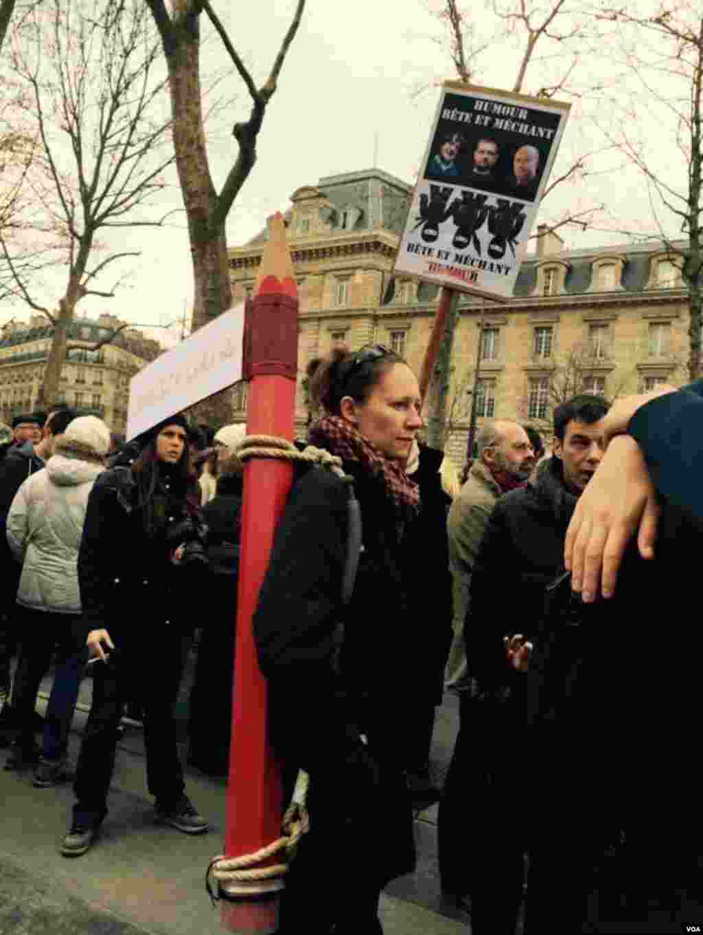 تظاهرکننده ای با بدوش کشيدن يک مداد بزرگ به کشتار نويسندگان و روزنامه نگاران اعتراض میکند ​-- ۲۱ دی ۱۳۹۳ (۱۱ ژانويه ۲۰۱۵)&nbsp;​عکس از محمد حسن مقصودلو، خبرنگار/عکاس بخش فارسی صدای آمريکا در پاريس