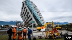 日本和台灣的救援人員在台灣花蓮市查看地震過後岌岌可危的大樓。