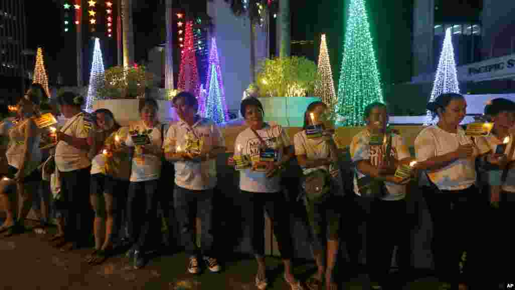Une foule allume des bougies près des messages et des fleurs déposés à l'extérieur de l'ambassade française, dans le quartier financier de la ville de Makati, Philippines,16 novembre 2015.