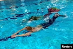 Pakar kesehatan Maija Mottonen dan muridnya Markus Parviainen dengan ekor putri duyung berenang di kolam renang, sebagai ilustrasi.(Foto: Reuters)