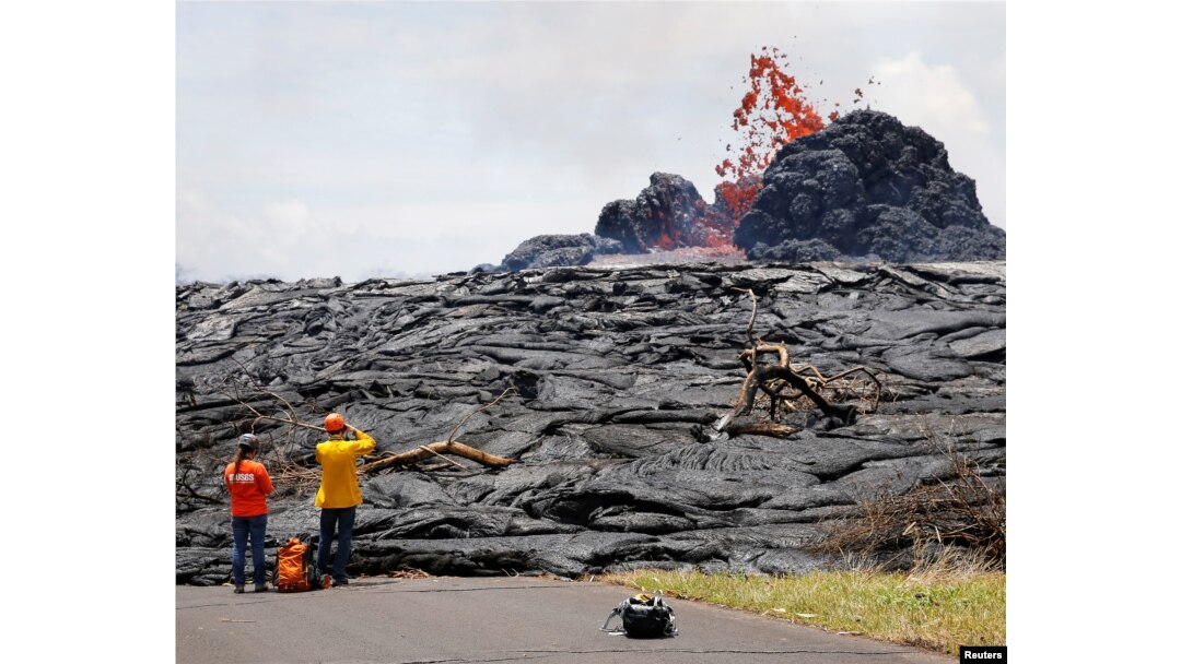 Sarah Conway, left, and Matt Patrick, both from USGS Hawaiian Volcano, watch lava erupting from a fissure in the Leilani Estates near Pahoa, Hawaii, May 24, 2018.