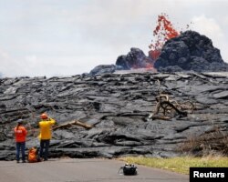 Sarah Conway, left, and Matt Patrick, both from USGS Hawaiian Volcano, watch lava erupting from a fissure in the Leilani Estates near Pahoa, Hawaii, May 24, 2018.