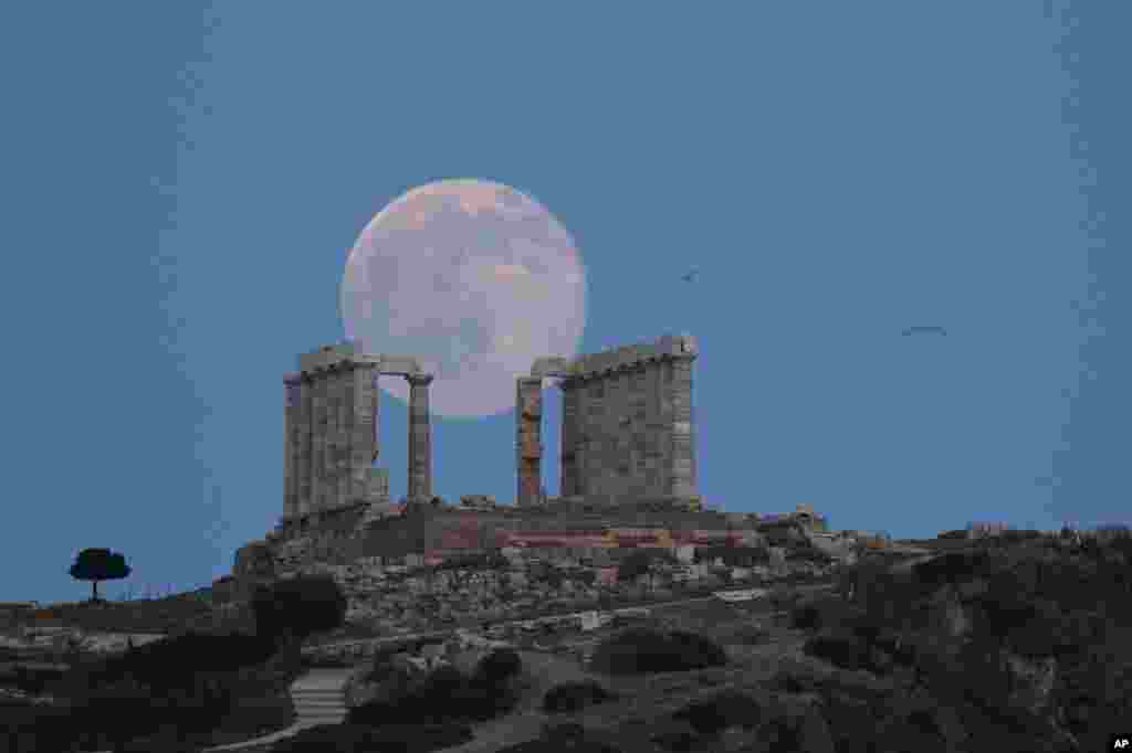 Trăng rằm mọc đằng sau Đền Poseidon cổ xưa bằng cẩm thạch ở Mũi Sounion, phía đông nam thủ đô Athens, Hy Lạp, trước hạ chí, ngày 20 tháng 6, 2016.
