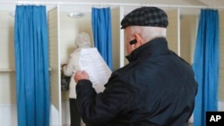 A man reads a ballot in front of a voting cabin at a polling station during a parliamentary elections in Baku, Azerbaijan, Nov. 1, 2015.