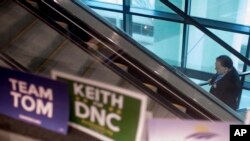 A man rides an escalator as campaign signs are seen before the general session of the Democratic National Committee winter meeting in Atlanta, Georgia, Feb. 25, 2017.